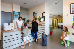 A reception area with a counter, a woman assisting a child, and another woman sitting on a stool. - Apartment in La Baule with Sea View (PORNICHET)