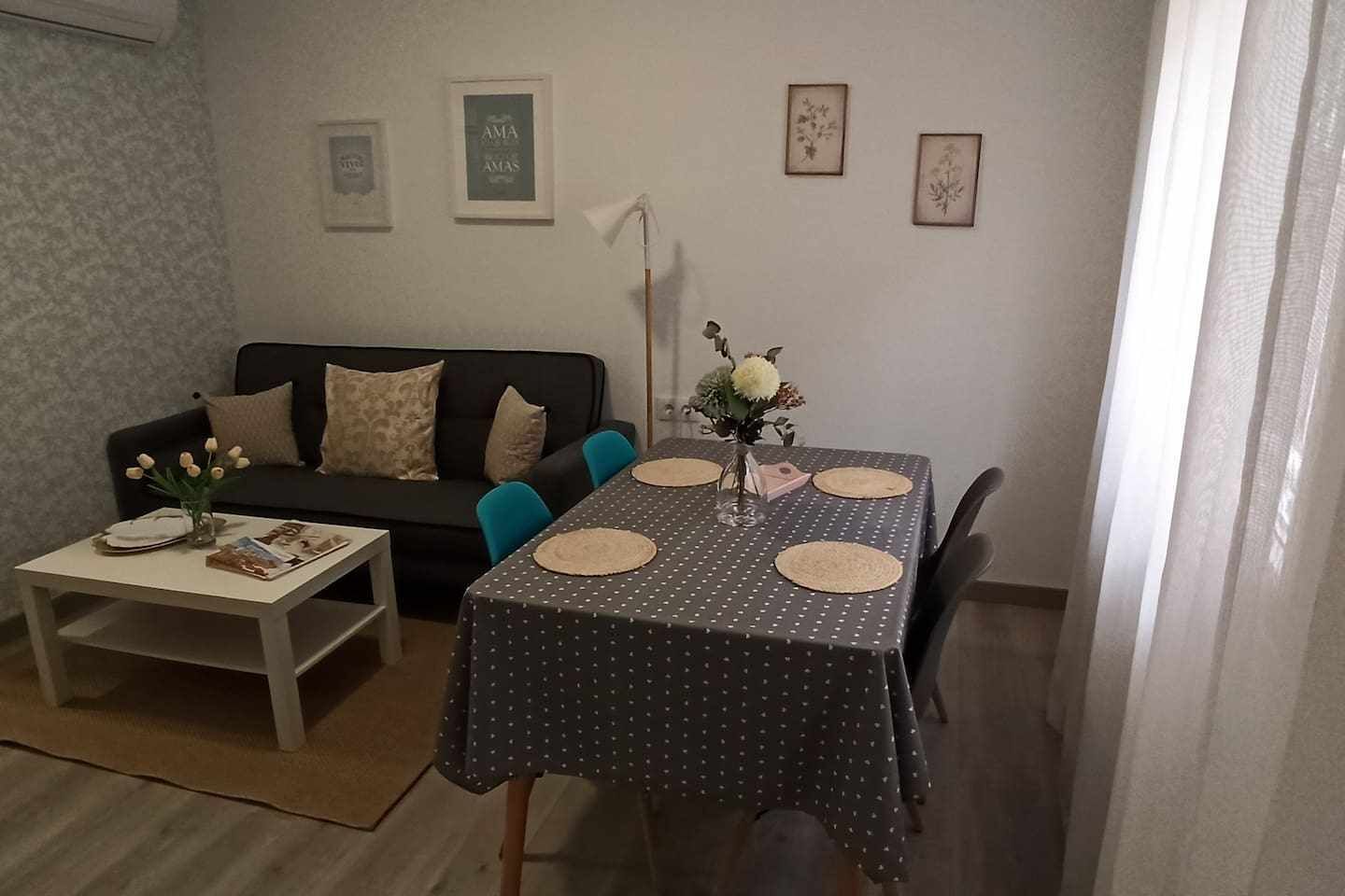 Een woonkamer met een bank, salontafel en een eettafel, gedekt met placemats.