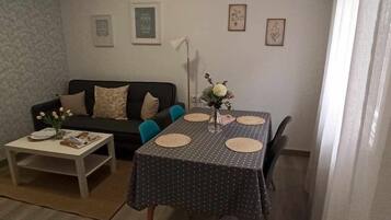 Een woonkamer met een bank, salontafel en een eettafel, gedekt met placemats.