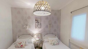 A bedroom with two beds, a decorative ceiling light, a bedside table with a lamp, and a wall with a dreamcatcher and a motivational quote. - Apartment amb Balcó (Consuegra)