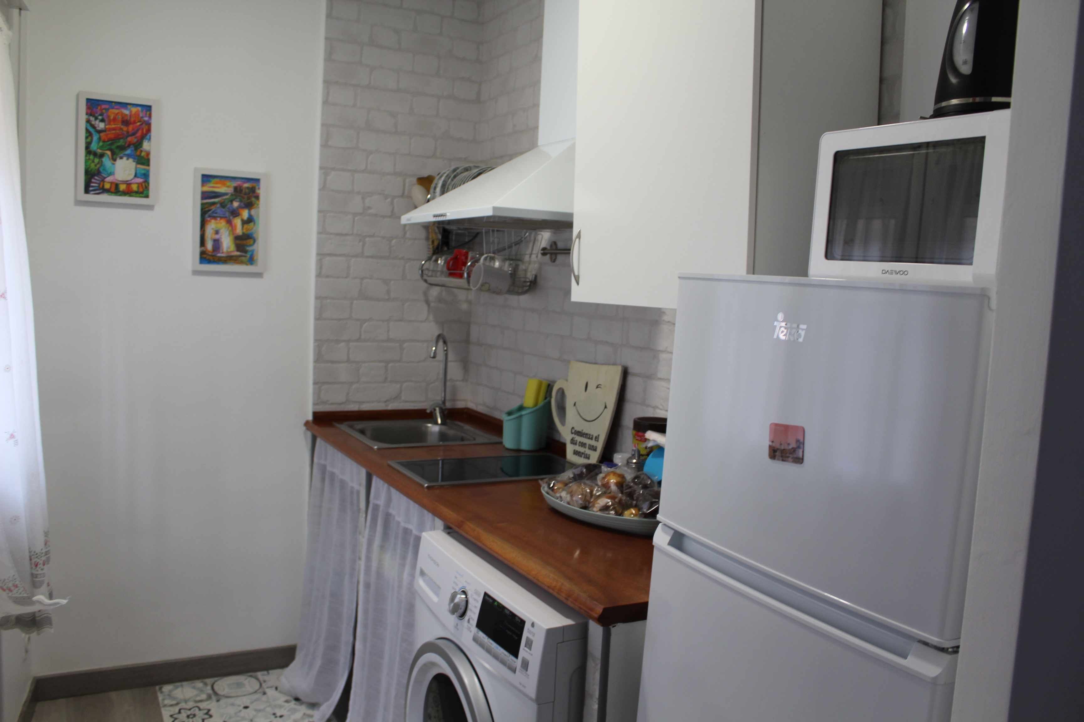 A compact kitchen with a washing machine, a refrigerator, and a sink.