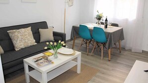 A living room with a sofa, coffee table, and a dining area with chairs and a table. - Apartment amb Balcó (Consuegra)
