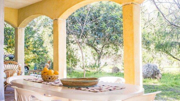 A covered outdoor seating area with a table, chairs, and a basket of lemons. - S'Omu e Mari by All4sardinia  (Cardedu)