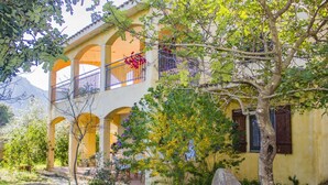 A yellow building with a covered patio and a balcony. - S'Omu e Mari by All4sardinia  (Cardedu)
