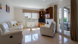 A living room with two sofas, a glass coffee table, a TV, and a bookshelf.