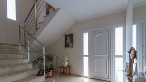 A staircase with metal railings, a potted plant, a lamp, and a door with glass panels.