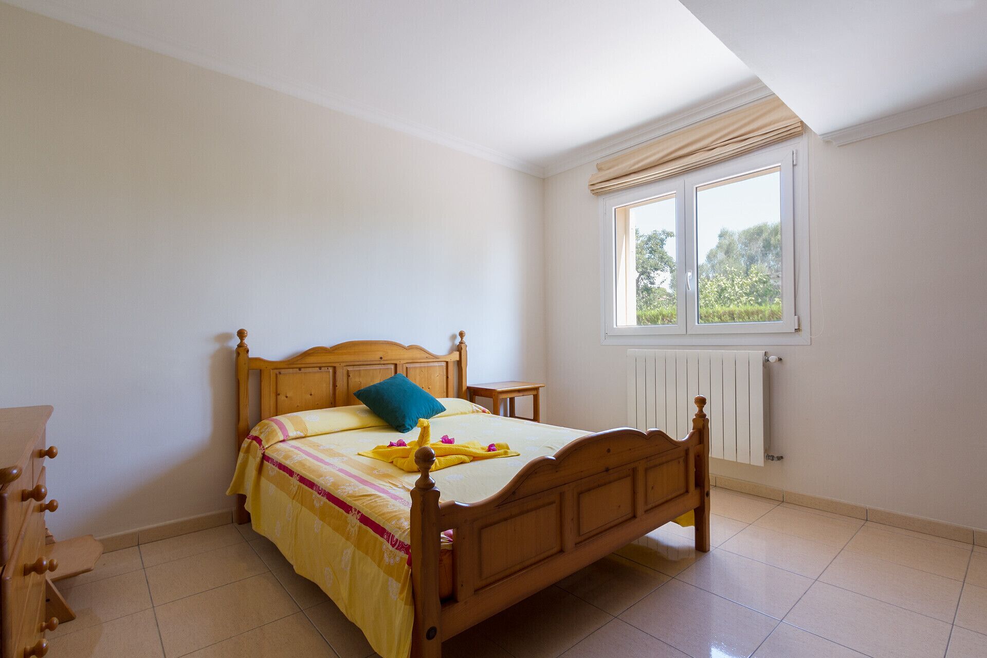 A bedroom with a wooden bed, a window with curtains, and a radiator.