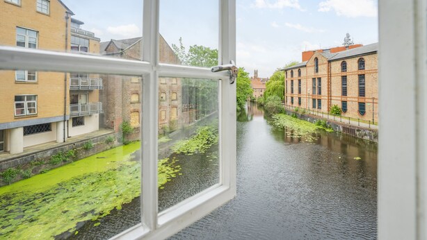 A view through a window of a canal with buildings on either side. - Cocoa Suites 45 - York city centre studio (sleeps 2) (York)