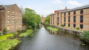 A canal with buildings on either side, a clear sky, and a distant tower. - Cocoa Suites 45 - York city centre studio (sleeps 2) (York)