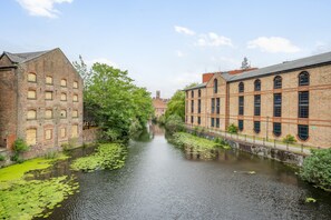 Un canal bordé de bâtiments des deux côtés, un ciel dégagé et une tour qui se profile à l’horizon.
