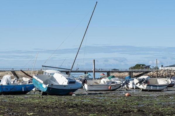 A row of boats docked at a pier with a clear view of the water and distant mountains.