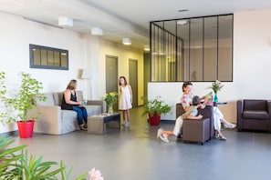 A modern lobby with seating areas, potted plants, and a large mirror.