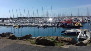 Um porto com vários barcos atracados, céu claro e água calma.