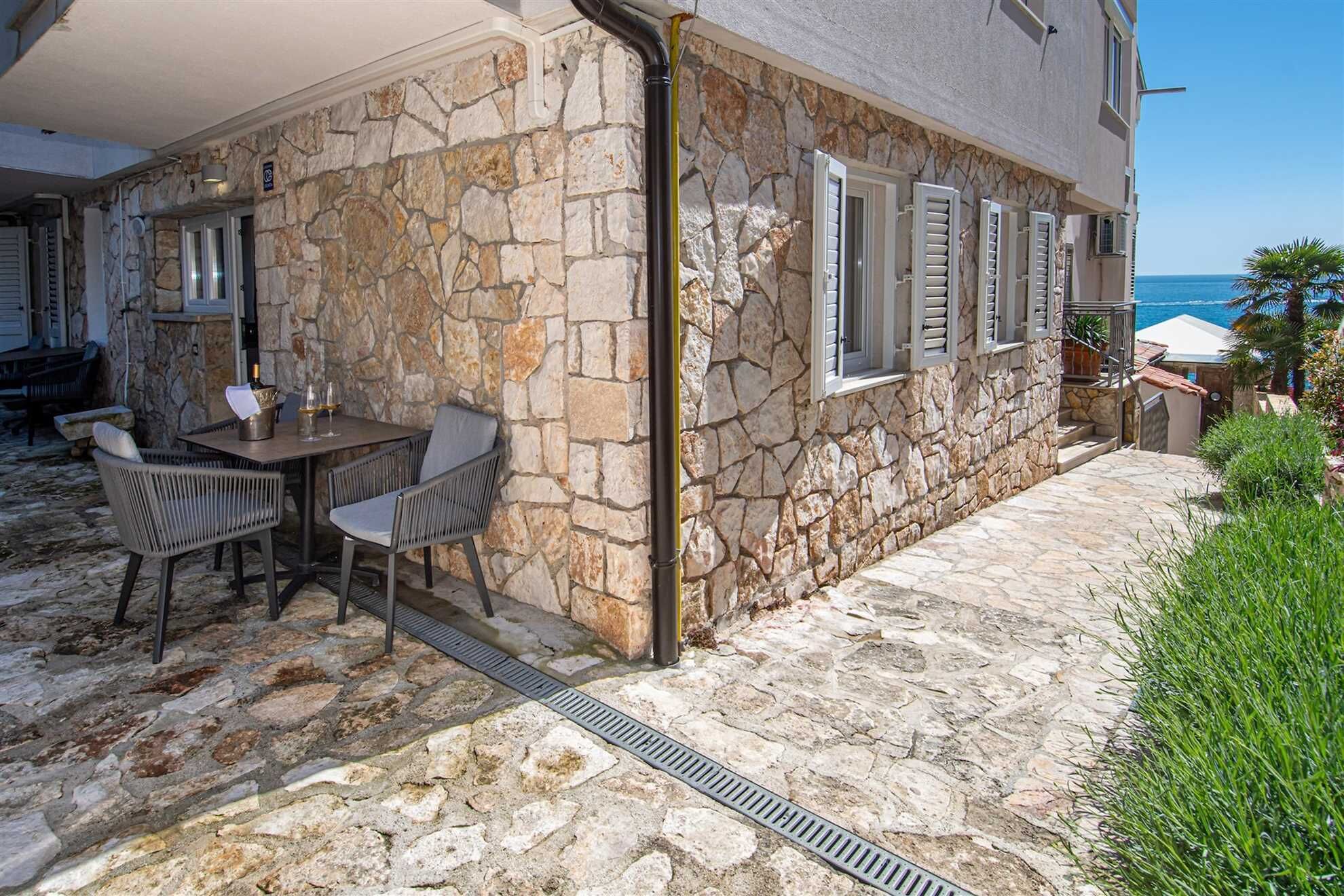 Un esterno in pietra con patio, posti a sedere all'aperto e vista sul mare.