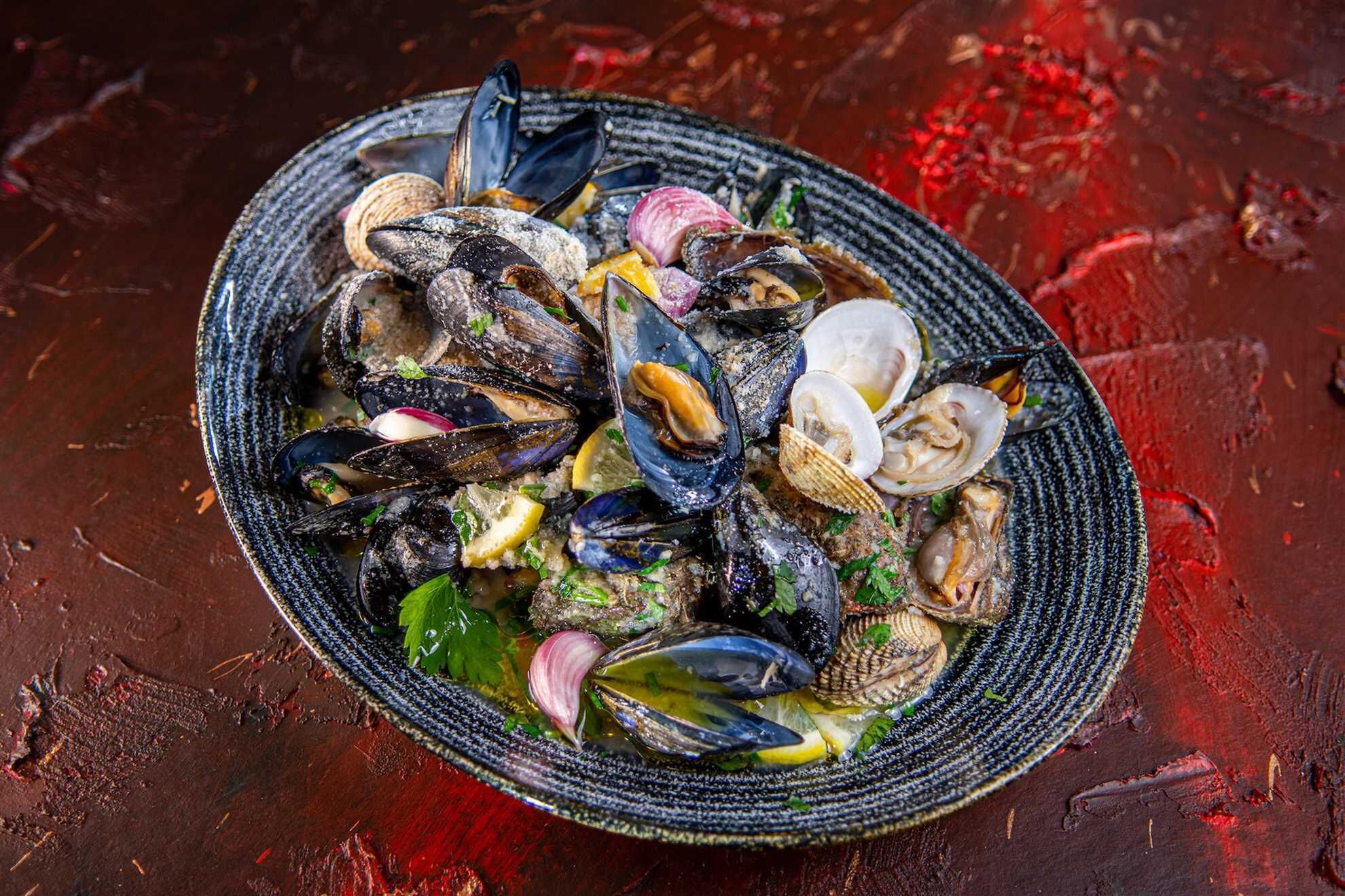 Un bol de mejillones con limón y hierbas.