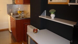 Une cuisine compacte avec des meubles en bois, un plan de travail blanc et un petit coin repas.