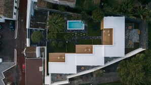 Ein Luftbild eines modernen Wohnhauses mit Schwimmbad, Terrasse und angelegtem Garten.