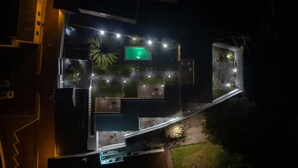 Ein modernes Gebäude mit Dachterrasse, Außenbereich und einer beleuchteten Grünfläche.