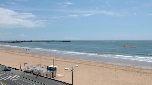 A beach with a road, a lifeguard tower, and a pier in the distance. - Apartment in La Baule near the Beach (PORNICHET)