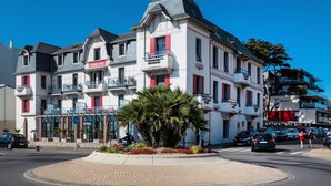 A multi-story hotel with balconies, a central courtyard with palm trees, and a clear blue sky. - Apartment in La Baule near the Beach (PORNICHET)