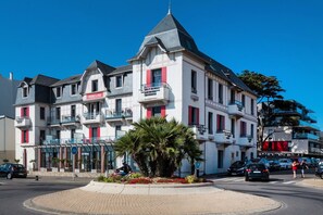 A multi-story hotel with balconies, a central courtyard with palm trees, and a clear blue sky. - Apartment in La Baule near the Beach (PORNICHET)