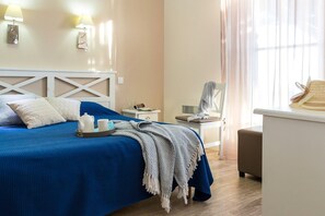 Ein Hotelzimmer mit Bett, Nachttisch, Stuhl und einem Fenster mit Vorhängen.