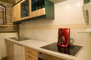 Une cuisine équipée d’une cuisinière intégrée, d’un évier et d’une machine à café rouge.