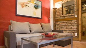 A living room with a sofa, a glass coffee table, and a bowl of fruit. - Apartment lower deck with balcony - Gohr apartments (Stralsund)