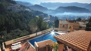 Piscina no terraço com vista desobstruída da paisagem circundante, incluindo edifícios distantes e montanhas.