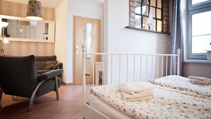 A bedroom with a bed, a chair, a lamp, and a window with curtains. - Fewo Ostwind 1 with small terrace - Gohr apartments (Stralsund)