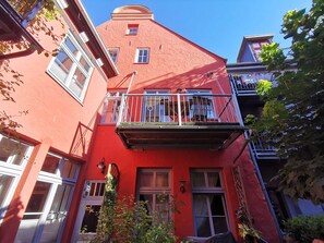 Um edifício vermelho com varanda, janelas e porta.
