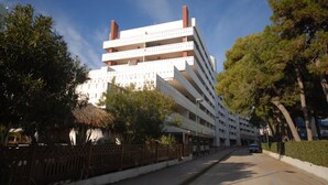 A multi-story hotel with a modern architectural design, featuring balconies on each floor and a central courtyard. - Bright flat with sea view (Lignano Sabbiadoro)