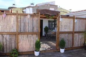 A wooden gate with a pergola, potted plants, and a patio area with a table and chairs. - Apartment 20 meters with terrace of 30 (Consuegra)
