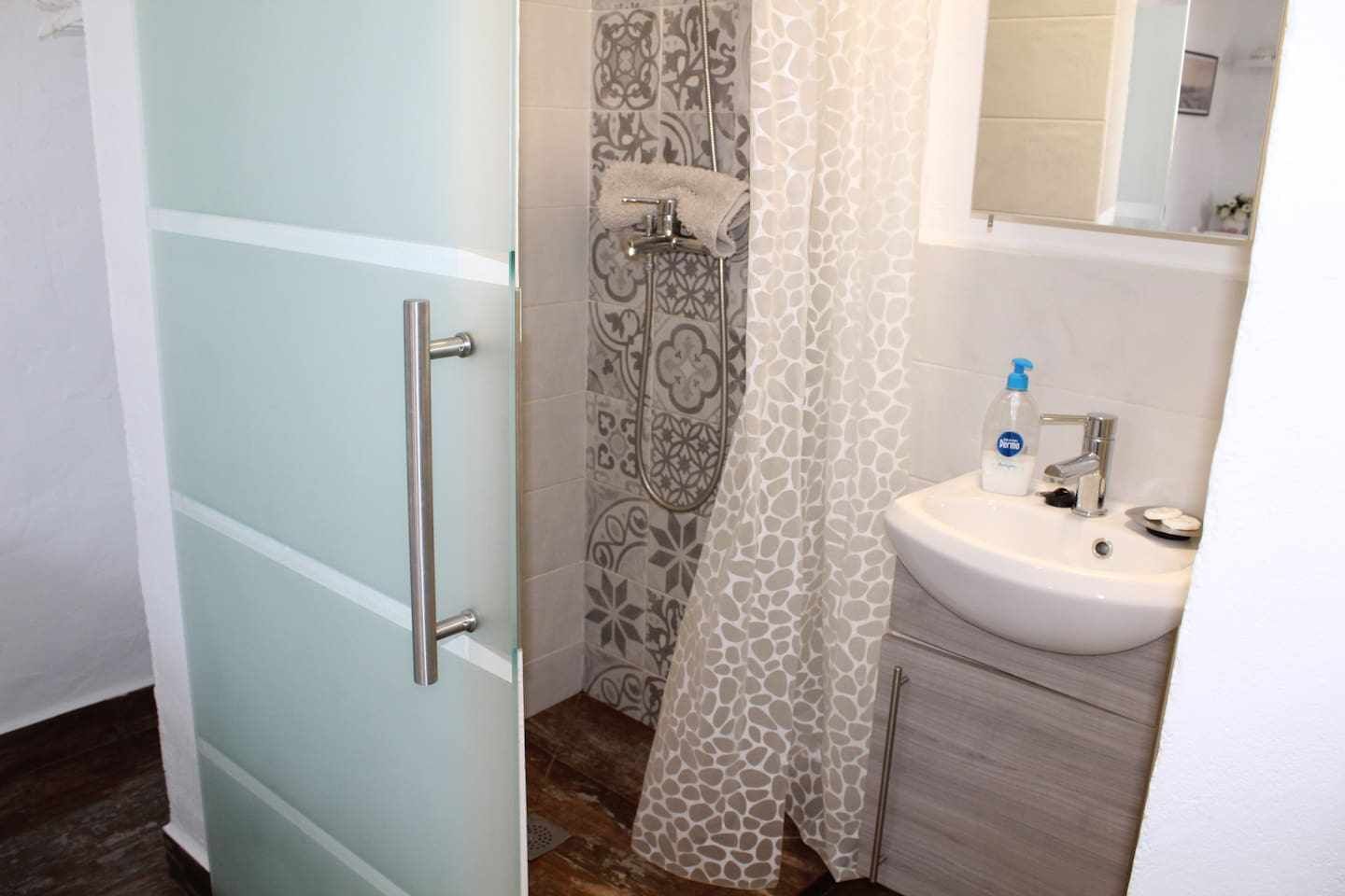 A bathroom with a shower, a sink, and a mirror.