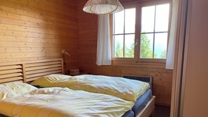 A wooden room with a bed, a window, and a lamp.