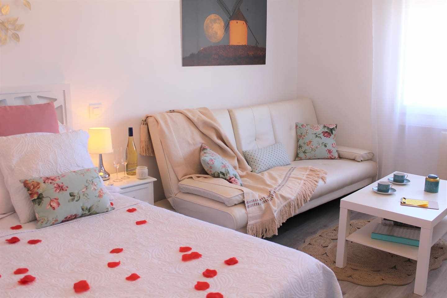 Een gezellige kamer met een bed, een bank, een nachtkastje en een klein tafeltje.