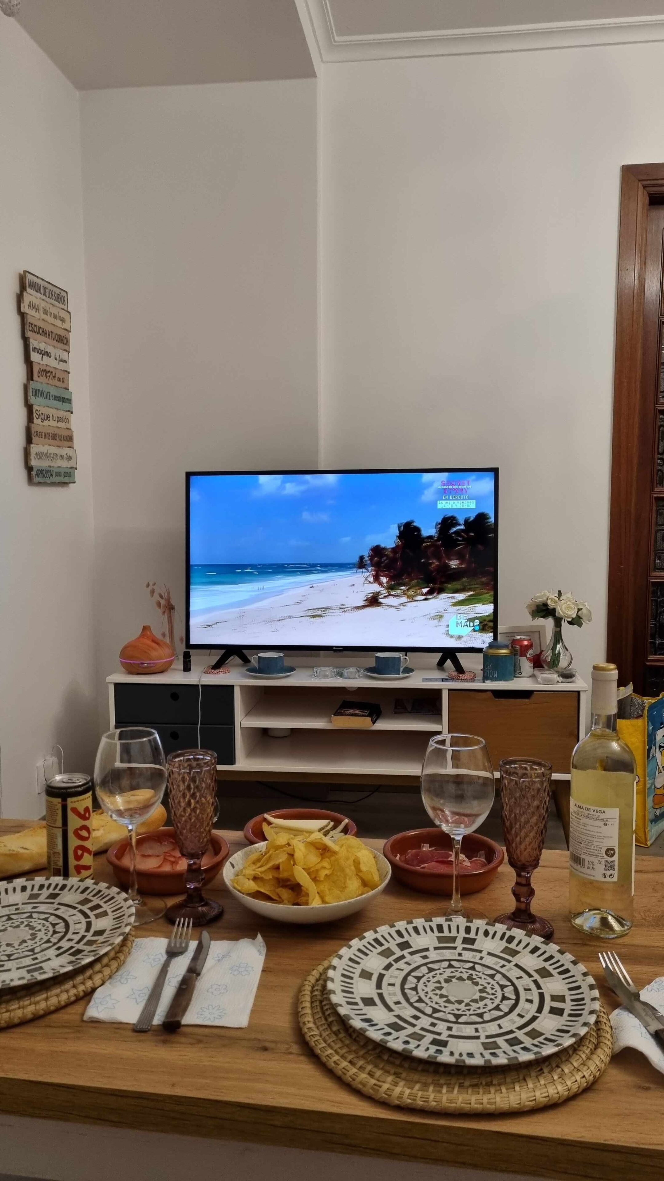 Ein an der Wand befestigter Fernseher zeigt eine Strandansicht.