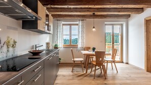 A modern kitchen with a wooden ceiling, a dining area with wooden chairs, and a view of the outdoors.