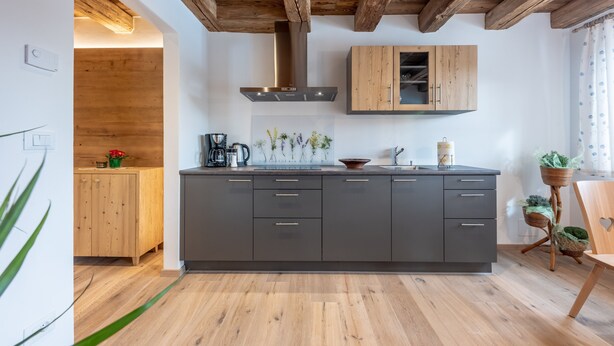 A modern kitchen with wooden beams, a central island, and built-in cabinets.