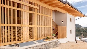 A wooden exterior with a stone base, a wooden staircase, and a view of the surrounding landscape.