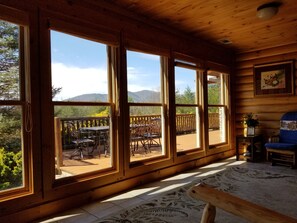 Eine Holzhütte mit großen Fenstern, einer Terrasse und Bergblick.