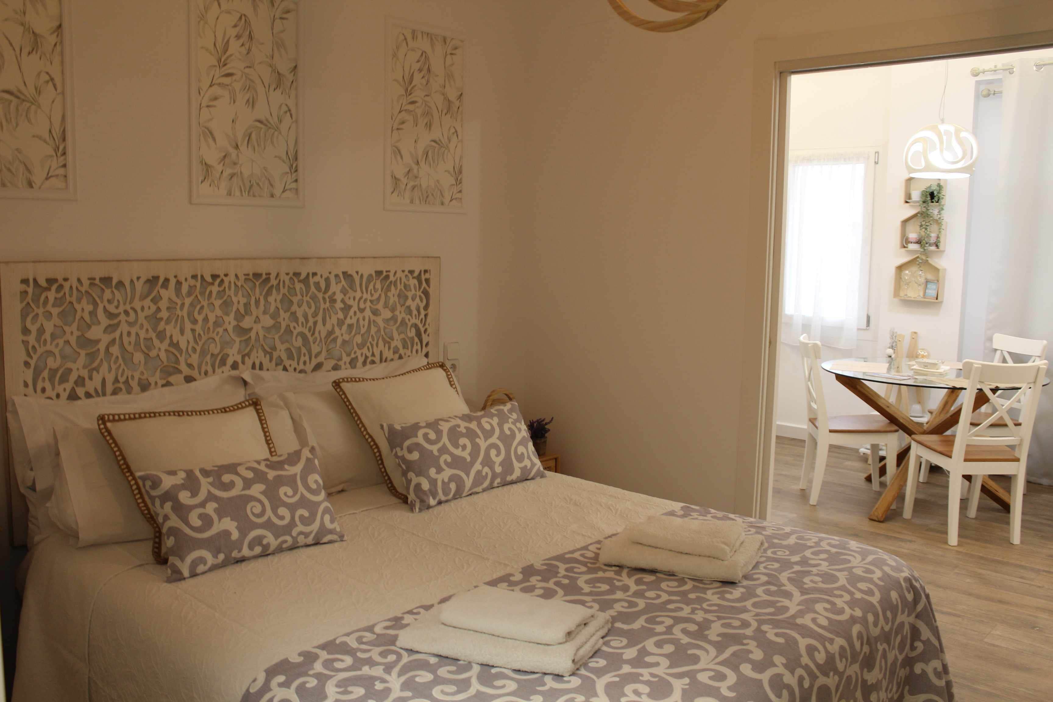 A neatly arranged bedroom with a large bed, a bedside table, and a chair.