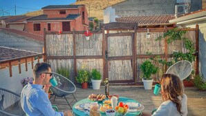Eine Terrasse mit rundem Tisch für zwei Personen, umgeben von Stühlen, mit Blick auf Windmühlen und Gebäude im Hintergrund.