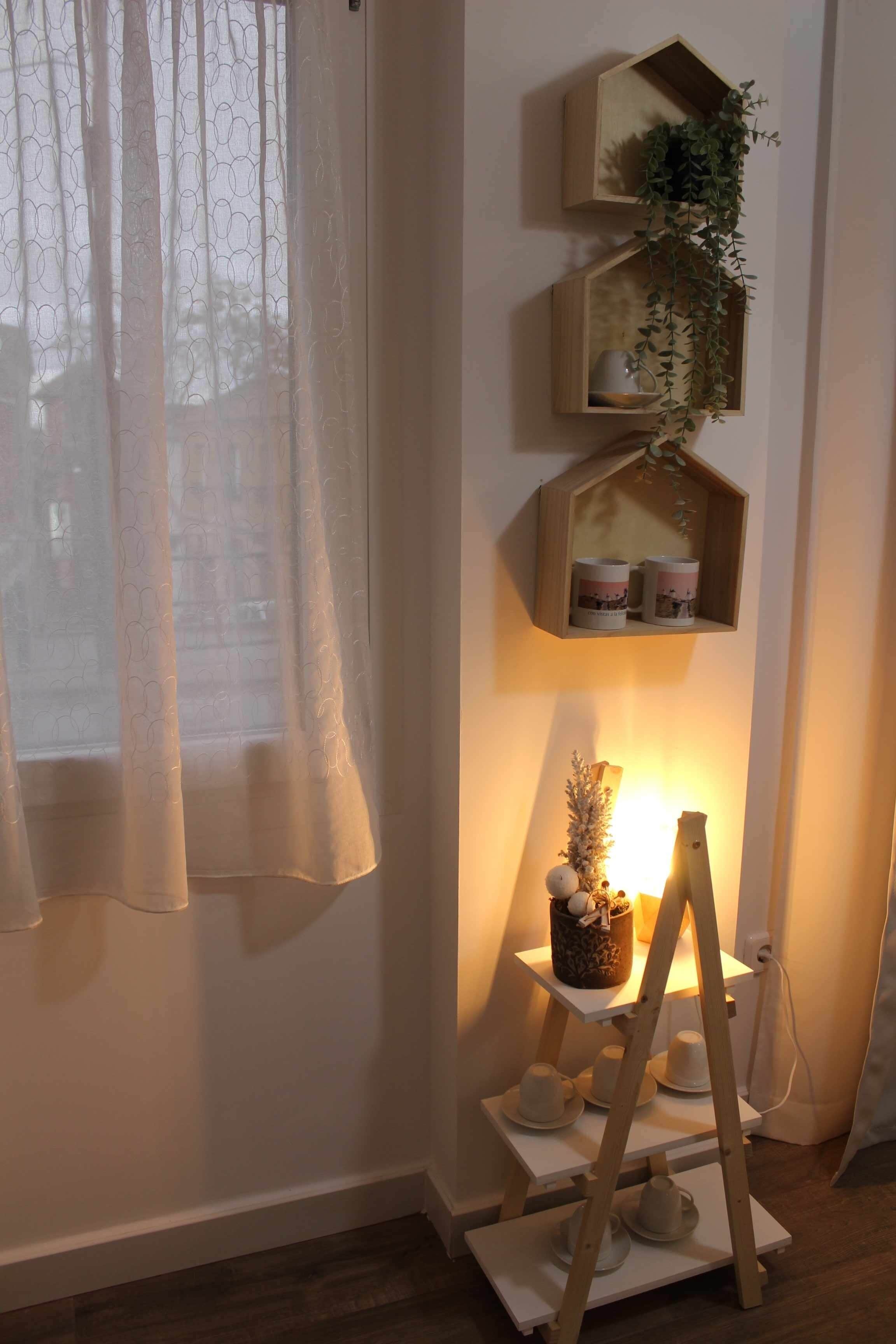 Una habitación con un estante de madera que contiene objetos decorativos y una pequeña planta en maceta.