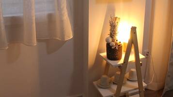 Una habitación con un estante de madera que contiene objetos decorativos y una pequeña planta en maceta.