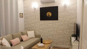Ein Wohnzimmer mit einer Couch, einem Couchtisch, einem Fernseher und einer Ziegelwand.