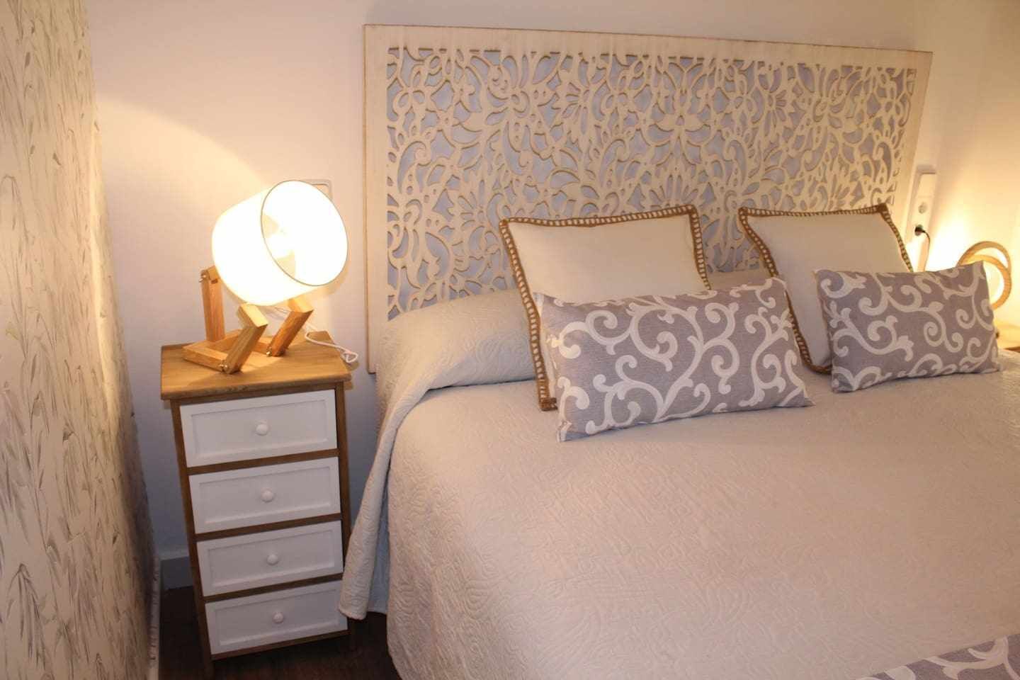 Een slaapkamer met een bed, twee bedlampen en een nachtkastje met lades.