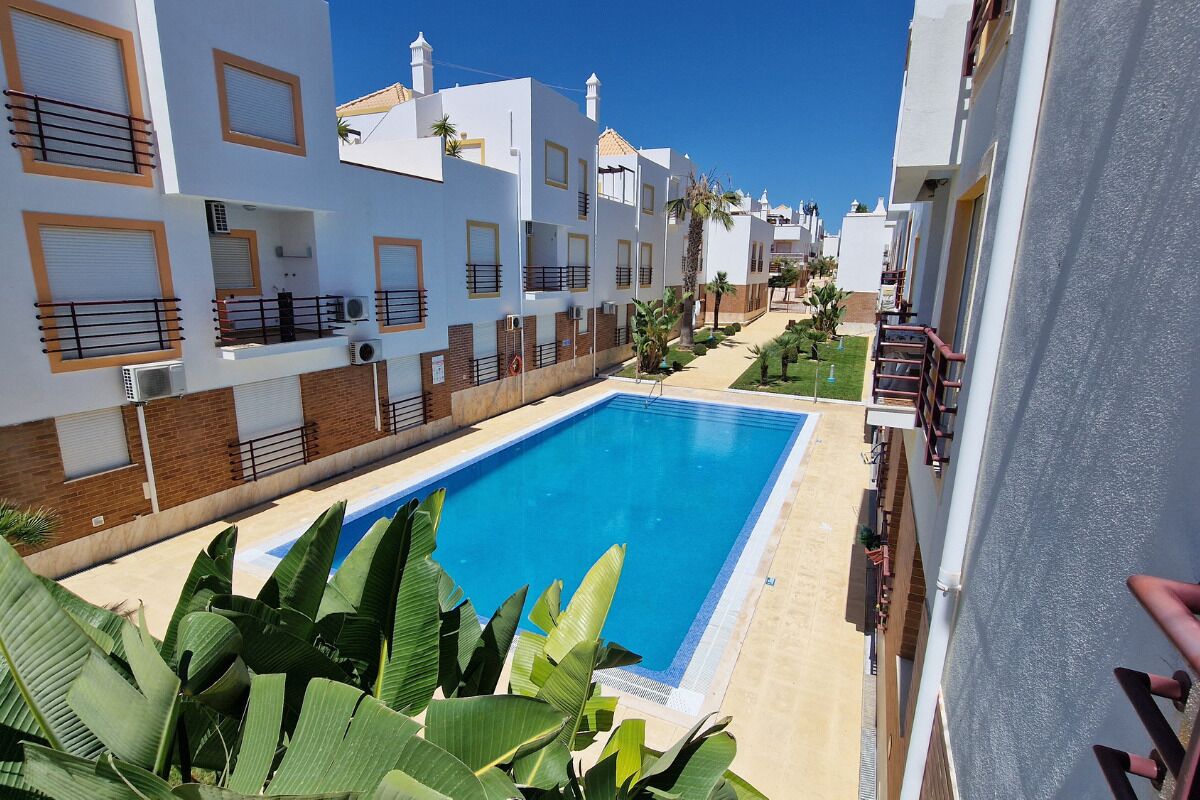 Un edificio residenziale con piscina, balconi e cielo azzurro.
