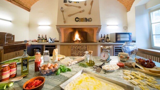 A kitchen with a brick ceiling, a fireplace, and various cooking utensils and ingredients on the counter. - Brunelleschi Apartment (Impruneta)