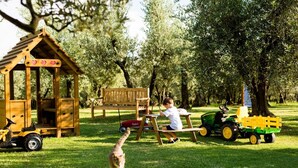 A wooden playhouse with a bench and a toy tractor. - Brunelleschi Apartment (Impruneta)